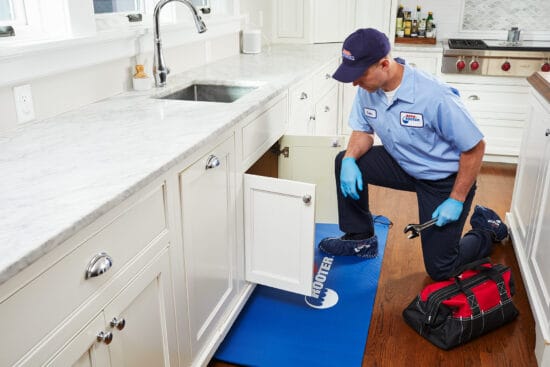 plumbing tech working under sink roto rooter